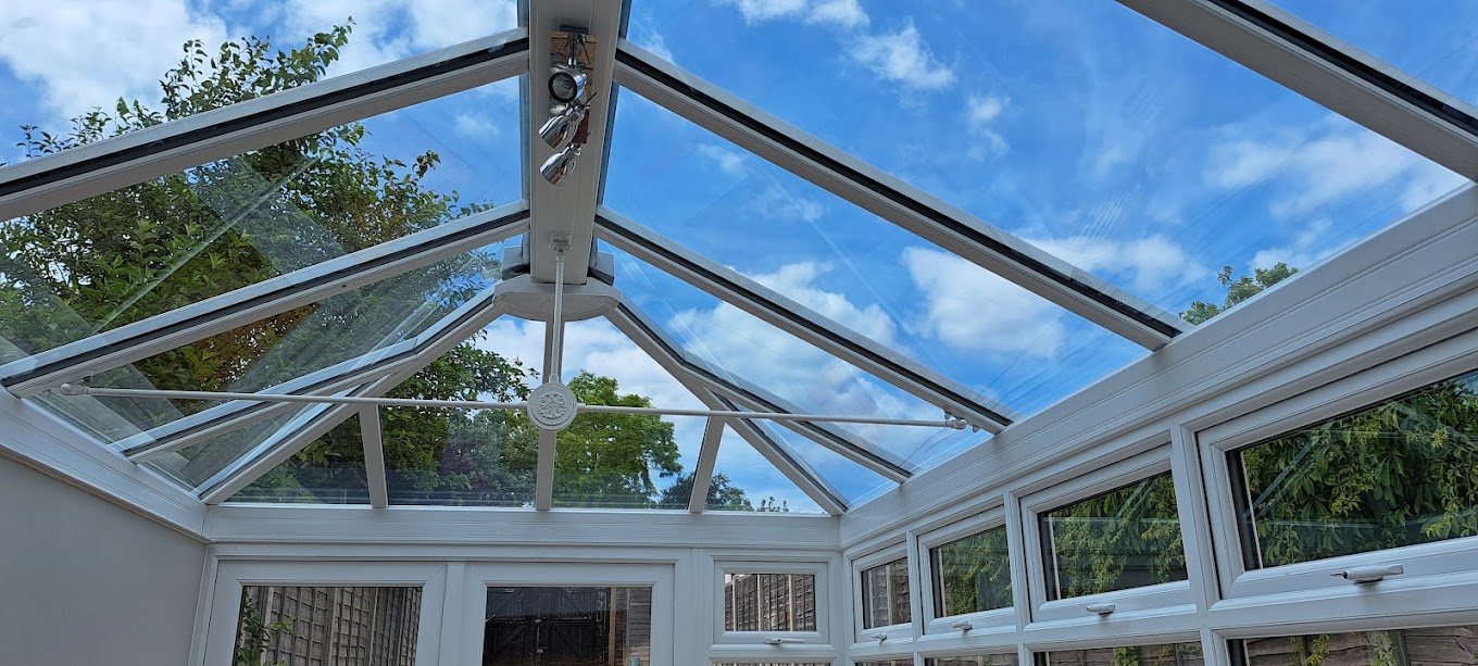 Interior of a glass conservatory looking up to the sky.